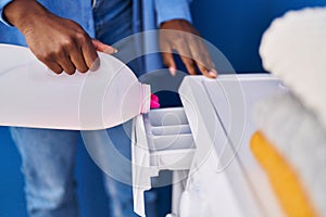 African american woman pouring detergent on washing machine at laundry room