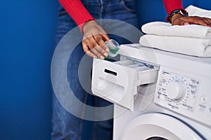 African american woman pouring detergent on washing machine at laundry room