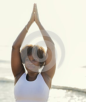 African American woman practicing yoga at the beach