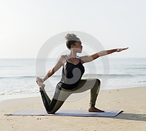 African American woman practicing yoga at the beach