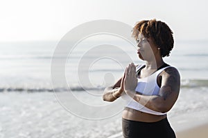 African American woman practicing yoga at the beach photo