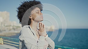 African american woman praying with closed eyes at seaside
