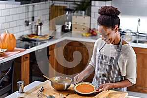 African american woman preparing pumpkin pie for holidays photo