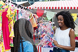 African american woman presenting colorful clothes at market
