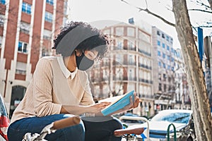 African American woman reading a book sitting on a bench. Latina woman with a book.