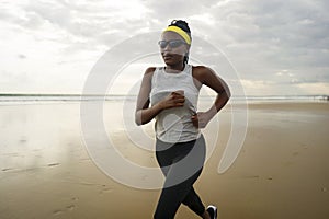 African American woman running on the beach - young attractive and athletic black girl training outdoors doing jogging workout at