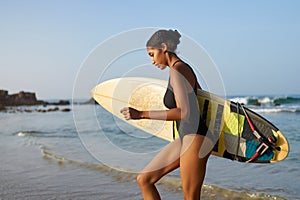 African american woman running with surfboard on ocean beach. Black female surfer with surf board. Pretty multiethnic