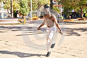 African american woman shirtless jumping at park