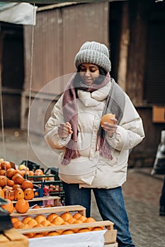 An African American woman is shopping at a local street market. He also chooses fresh fragrant fruits.