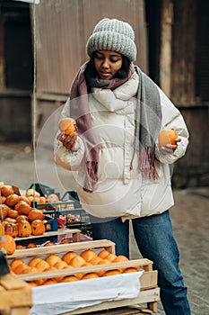 An African American woman is shopping at a local street market. He also chooses fresh fragrant fruits.