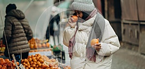 An African American woman is shopping at a local street market. He also chooses fresh fragrant fruits.