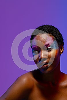 African american woman with short hair and colourful makeup looking away, copy space