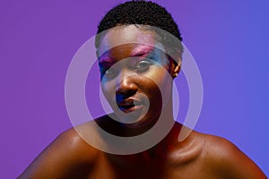 African american woman with short hair and colourful makeup on purple background