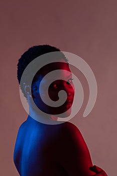 African american woman with short hair looking ove shoulder in red and blue light, copy space photo