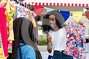 African american woman showing clothes to buyer at market