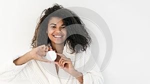 African american woman showing cream jar on camera