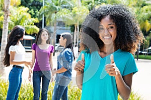 African american woman showing thumb with group of girlfriends