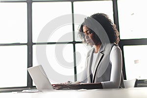 An African-American woman sits and uses laptop