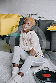 African american woman sitting on carpet and listening music