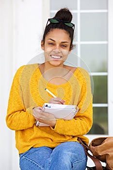 African american woman sitting outside writing in book