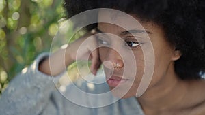 African american woman sitting with serious expression at park