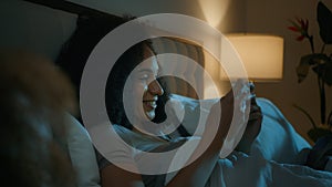 African American woman sleepless girl happy insomniac teen playing online game illuminated with mobile phone screen on