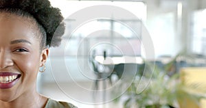 African American woman smiles brightly in a well-lit business office space with copy space