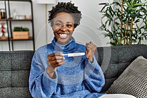 African american woman smiling confident holding pregnancy test at home