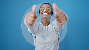 African american woman smiling with thumbs up over isolated blue background