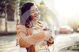 African american woman standing in a srteet with takeaway coffee cup photo