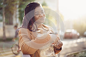 African american woman standing in a srteet with takeaway coffee cup photo