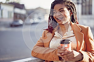 African american woman standing in a srteet with takeaway coffee cup photo