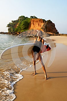 African american woman standing with surfboard on ocean beach. Black female surfer posing with surf board. Pretty