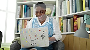 African american woman student using laptop studying at library university