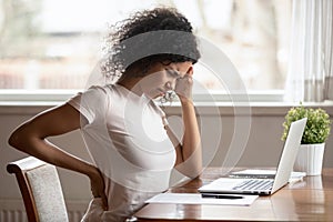 African American woman suffer from backache working at table