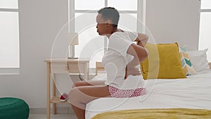 African american woman suffering for back injury sitting on bed at bedroom