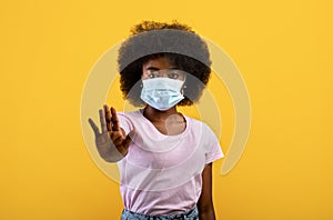 African american woman suffering from sick, wearing mask and comply with social distance, standing on yellow background photo