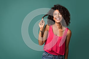 African-american woman touching her curly hair on turquoise background