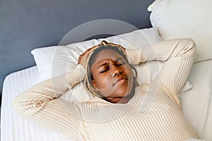 african american woman trying to sleep but headache makes it difficult