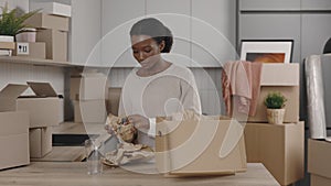 African american woman unpack things from the box at new home. Relocation unpacking interior objects from cardboard