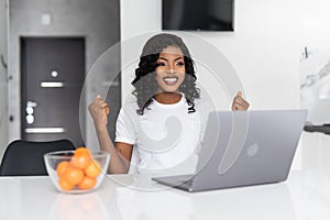 African american woman using laptop at kitchen very happy and excited, winner expression celebrating victory screaming with big