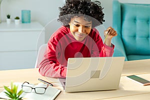 African american woman using laptop shopping online paying with gold credit card. Girl sitting at home buying on