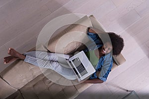 African American woman using laptop on sofa top view