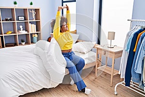 African american woman waking up stretching arms at bedroom