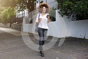 African american woman walking and looking at cellphone