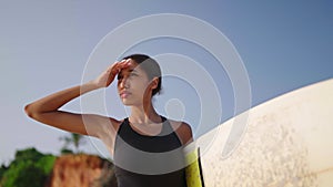 African american woman walking with a surfboard on ocean beach. Black female surfer going with surf board. Pretty