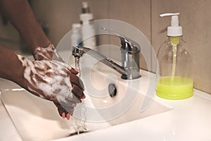 African-American woman washes hands. Cropped image of person washing hands at sink in bathroom, Coronavirus hand washing for clean