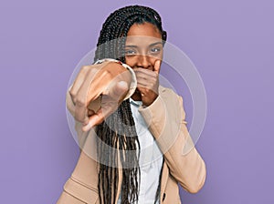 African american woman wearing business jacket laughing at you, pointing finger to the camera with hand over mouth, shame