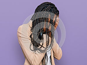 African american woman wearing business jacket with sad expression covering face with hands while crying