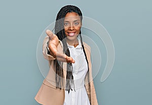 African american woman wearing business jacket smiling friendly offering handshake as greeting and welcoming